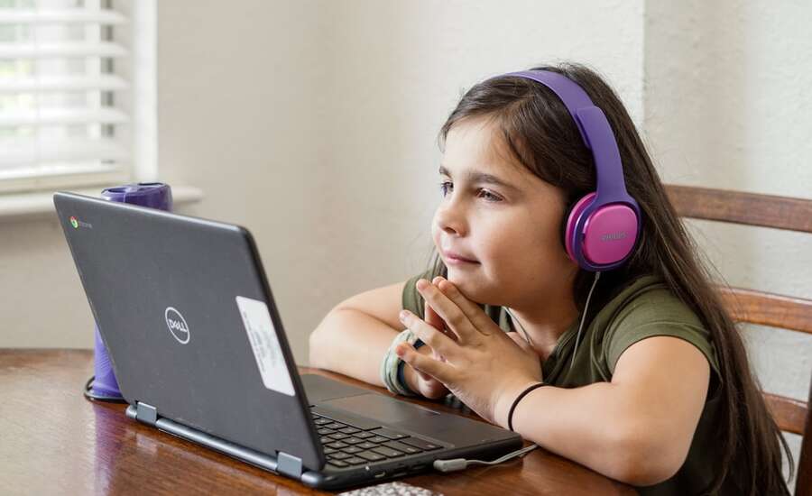 girl with headphones on looking at a laptop
